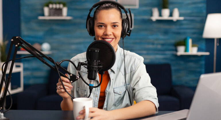 Influencer wearing headphones recording new podcast series at home studio for youtube channel.